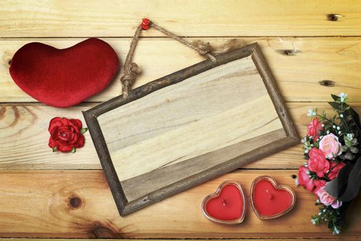 Top view of empty wooden sign next heart sign candle in glass and flowers over old wood, vintage background ready to put photographs or text.