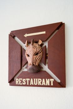 Wooden restaurant sign with a zebra head and a white arrow