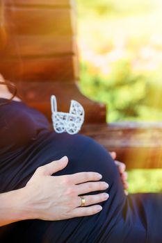 toy baby carriage on the belly of a pregnant woman. concept idea