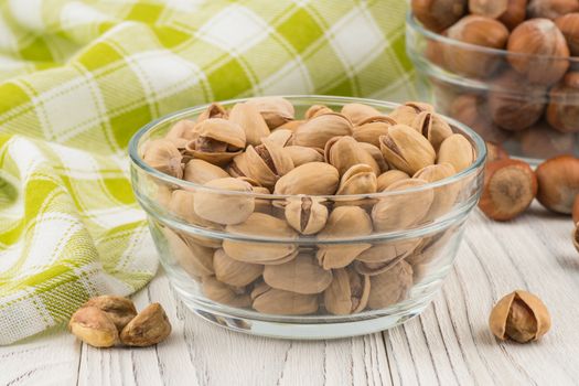 Pistachios in a glass bowl on the old wooden table.  Selective focus. 