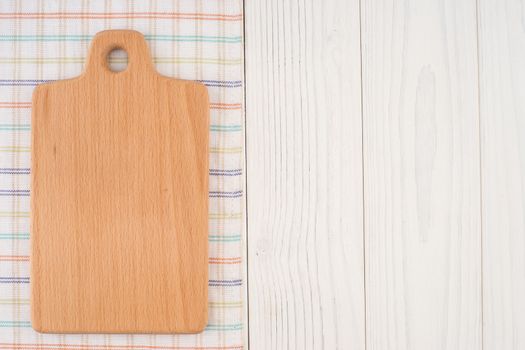 Cutting board on a kitchen napkin on old wooden table. Top view.