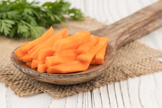 Sliced carrots in a spoon and an old wooden table. selective focus.