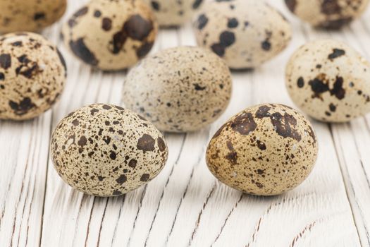 Quail eggs on old white wooden table. Selective focus.