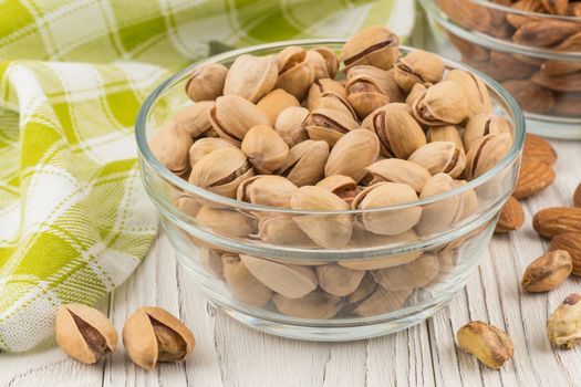 Pistachios in a glass bowl on the old wooden table.  Selective focus. 