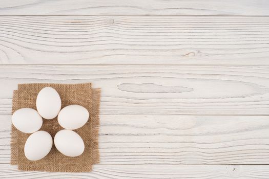 Chicken eggs on white old wooden table. Top view.