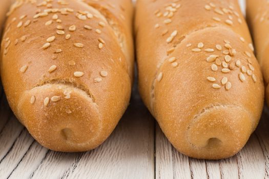 Bun with sesame seeds on old white wooden table. Selective focus.