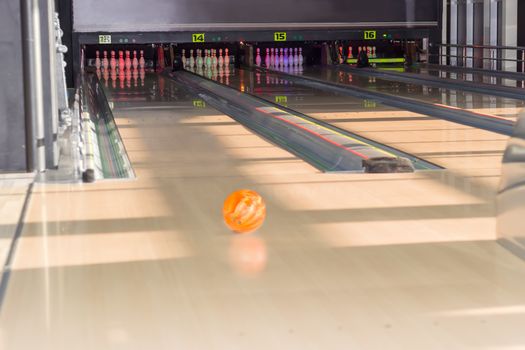 Several lanes with bowling pins and bowling ball on the foreground in a modern pin bowling alley
