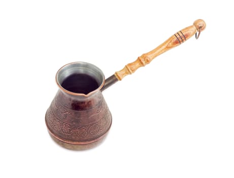 Empty old copper coffee pot with a wooden handle on a light background
