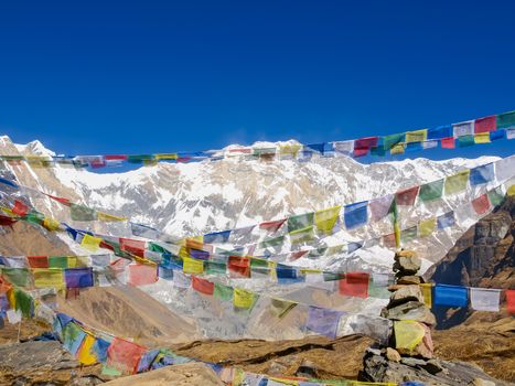 View of the south face of Annapurna I Main Mountain across the colorful prayer flags on the background of sky in morning in the Himalayas
