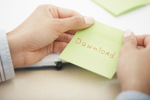 Hands holding sticky note with Download text