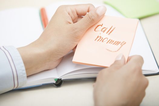 Hands holding sticky note with Call mommy text