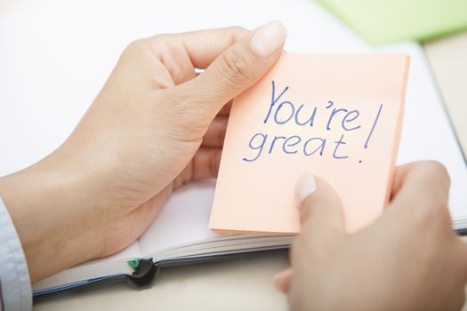 Hands holding sticky note with You are great text