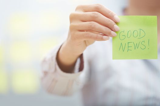 Woman holding sticky note with Good news text