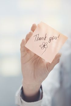 Woman holding sticky note with Thank you text