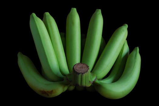 Raw green banana on black background.