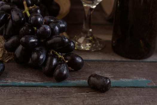 Black grapes and wine on a wooden table old.