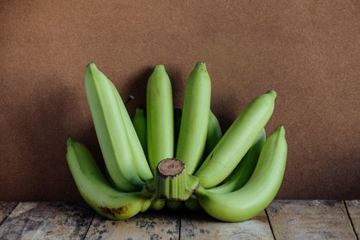 Raw green bananas on old wood.