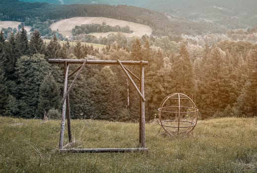 Dreamy abandoned playground with overgrown grass in the forest in warm colours, nostalgic lonelines abandonment neglect, lost childhood