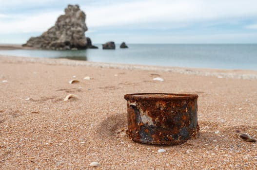 Rusty tin can on beach - concept of environment background