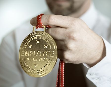 Employee holding golden medal with the text employee of the year. Incentive or motivation concept