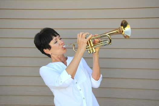 Mature female beauty blowing her trumpet outside.