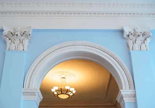 white arch on a blue wall inside the building and two pilasters