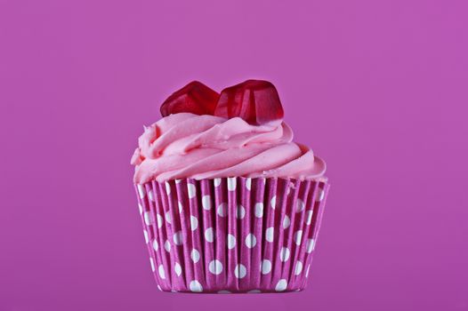 Sweet cupcake with jelly isolated on a pink background 