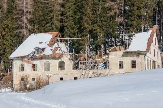 mountain house abandoned with damaged roof. winter season, snow around