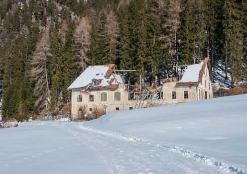 mountain house abandoned with damaged roof. winter season, snow around