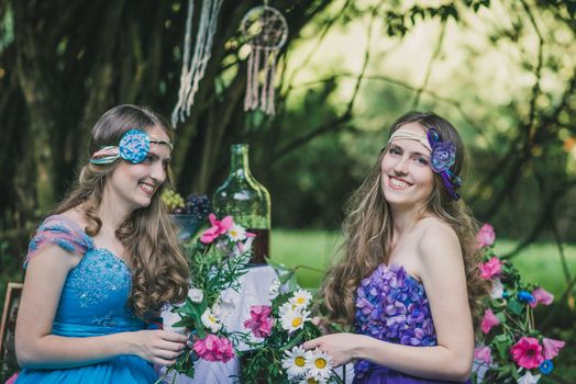 two adult sisters are twins with flowers in the summer garden