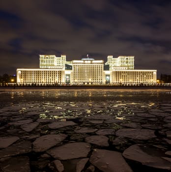 Russian Ministry of Defense in the evening in winter on a background of cloudy sky. On the foreground is Moscow River covered by ice floes.