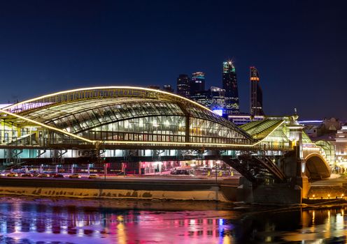 Night winter panorama of the Moskva River embankment - skyscrapers of Moscow International Business Center "Moscow-City," pedestrian bridge Bogdan Khmelnitsky. Rich colorful illuminations and reflections in the river.