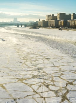 Panorama of the frozen, covered with ice floes Moscow River and Frunze Embankment, on the background the Ministry of Defence and the Pushkin bridge, back lit photo in cold sunny winter day.