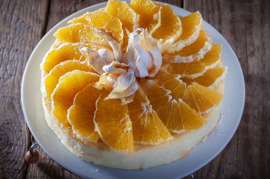 Cheesecake decorated with oranges and physalis on a table