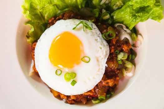 fried noodle with minced pork and fried egg on white dish