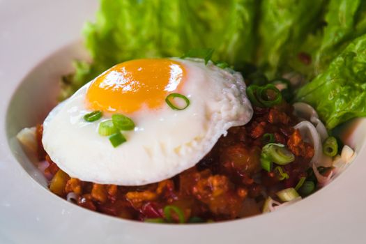 fried noodle with minced pork and fried egg on white dish