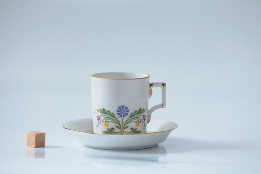 beautiful white mug with a flower and a piece of sugar isolated on white