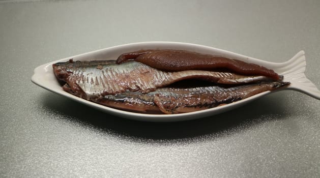 Salted herring on a plate in the form of fish
