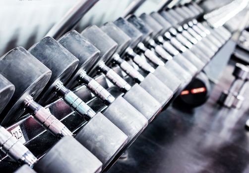 Rows of dumbbells in gym with hign contrast and monochrome color tone. Copy space