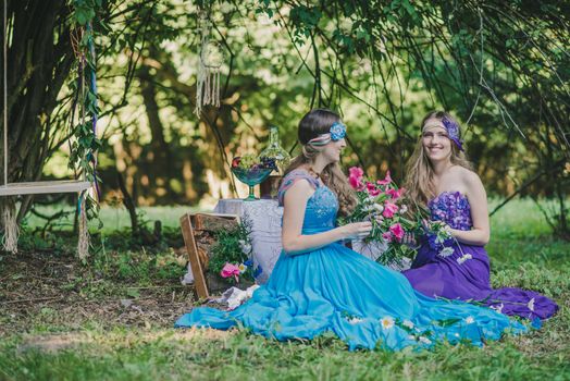 two adult sisters are twins with flowers in the garden