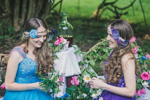 two adult sisters are twins with flowers in the summer garden