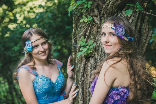 two sisters, twins from near tree in summer