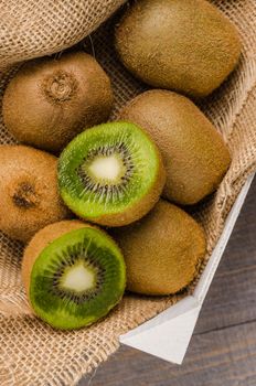 Box of fresh kiwi in on wooden background. Top view with copy space