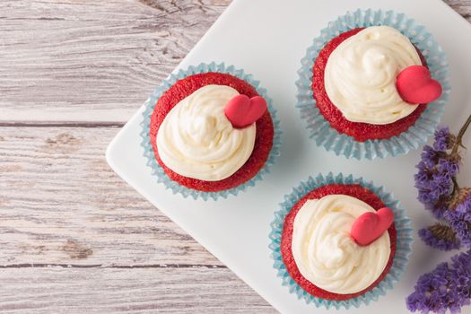 Red velvet heart cupcakes with cream cheese frosting and a red heart for Valentine's Day. Top view with copy space