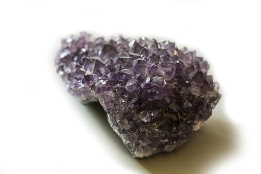 An amethyst stone placed on the white background. Horizontal studio shot.