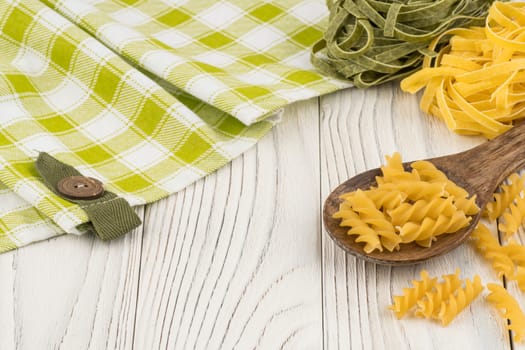 Pasta in a wooden spoon on old wooden table. Selective focus.