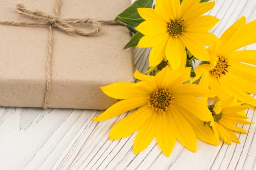 Gift box with a field flower on a white wooden table. Selective focus.