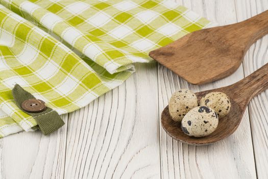 Quail eggs in a wooden spoon and an old wooden table. Selective focus.