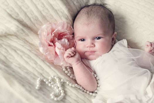 Newborn baby girl in fshionable dress with flower and pearl beads