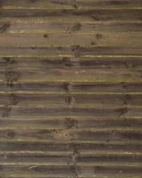 Horizontal running grungy brown stained and greened planks and boards from a waterfront cottage.